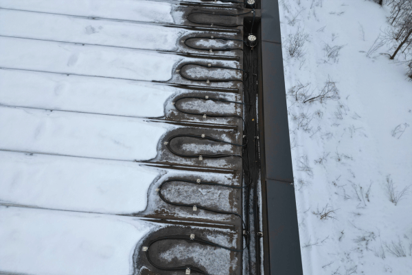 Toit plat avec câbles chauffants dégageant des zones de neige pour prévenir l'accumulation de glace.